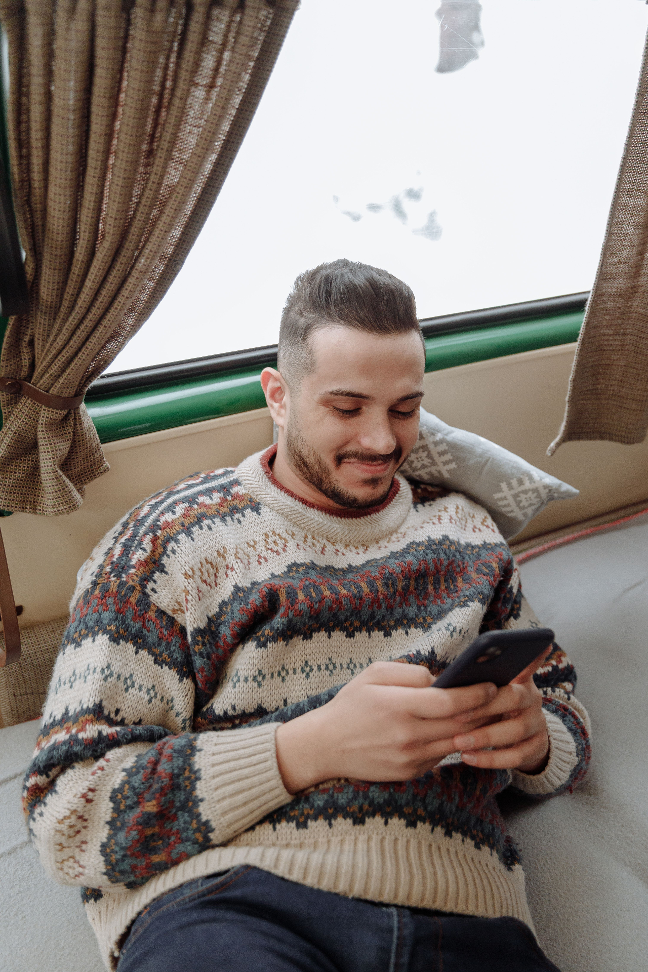 A smiling man relaxing at home while using his phone for virtual therapy