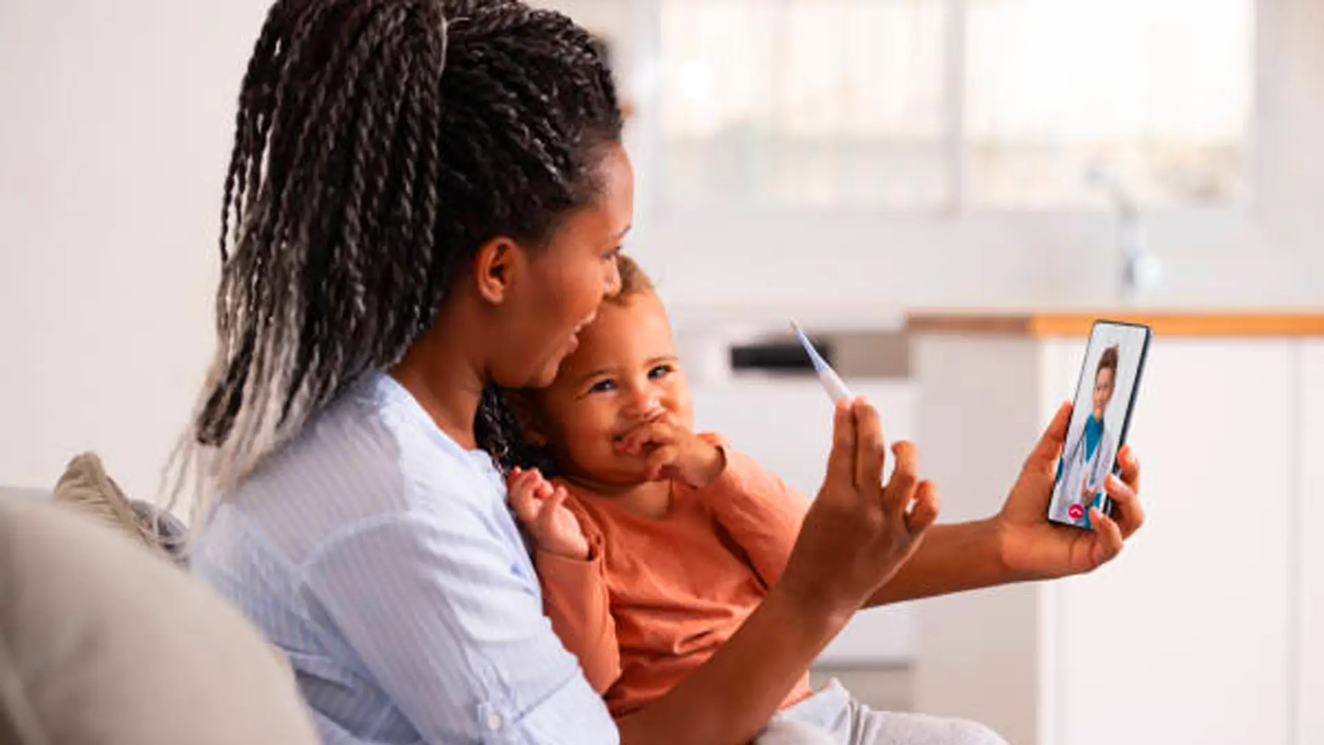Mother holding baby during a virtual appointment on a smartphone