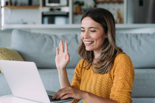 A woman waving during a virtual video call with her clinician